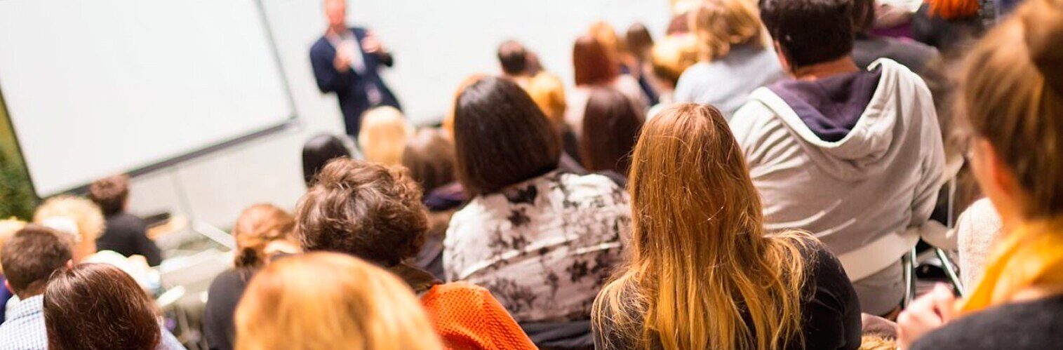 Engaged audience members listen attentively to a speaker during a professional development seminar or workshop presentation.