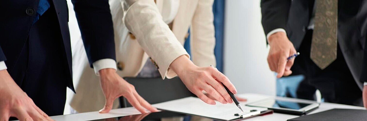 Business team collaborating around a table, pointing at documents during a meeting.