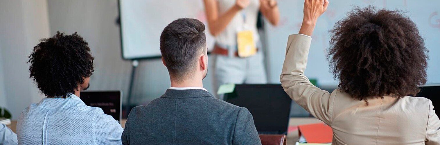 Participant raising her hand to ask a question during a business presentation or training session.