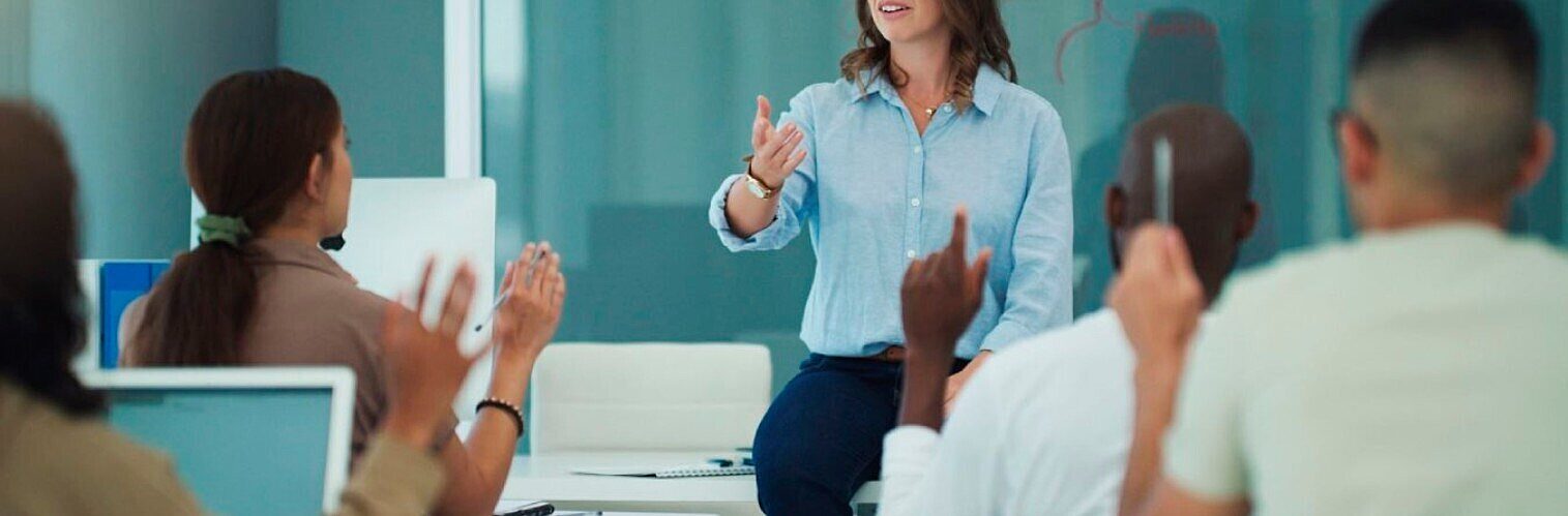Businesswoman leading a presentation or training session for a diverse group of colleagues in an office meeting.
