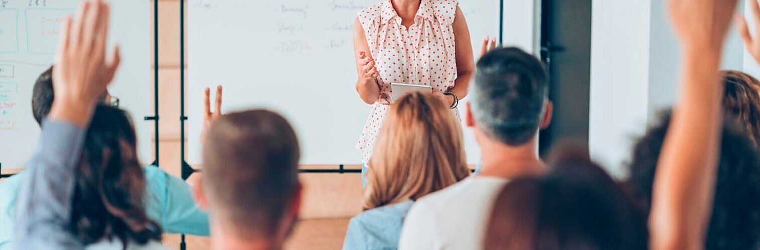Participants raising hands to ask questions during an interactive training session or workshop.