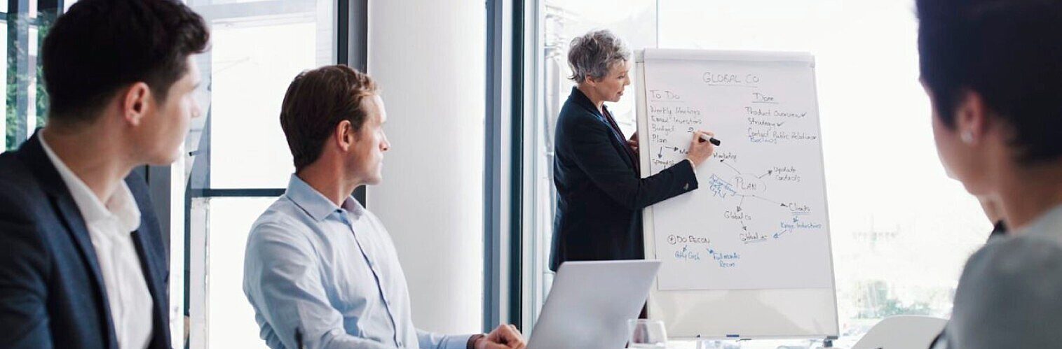 Close-up of business colleagues analysing financial data, pointing with pens at charts and graphs on documents during a meeting.