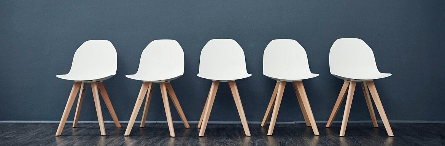 Five empty white chairs in a row
